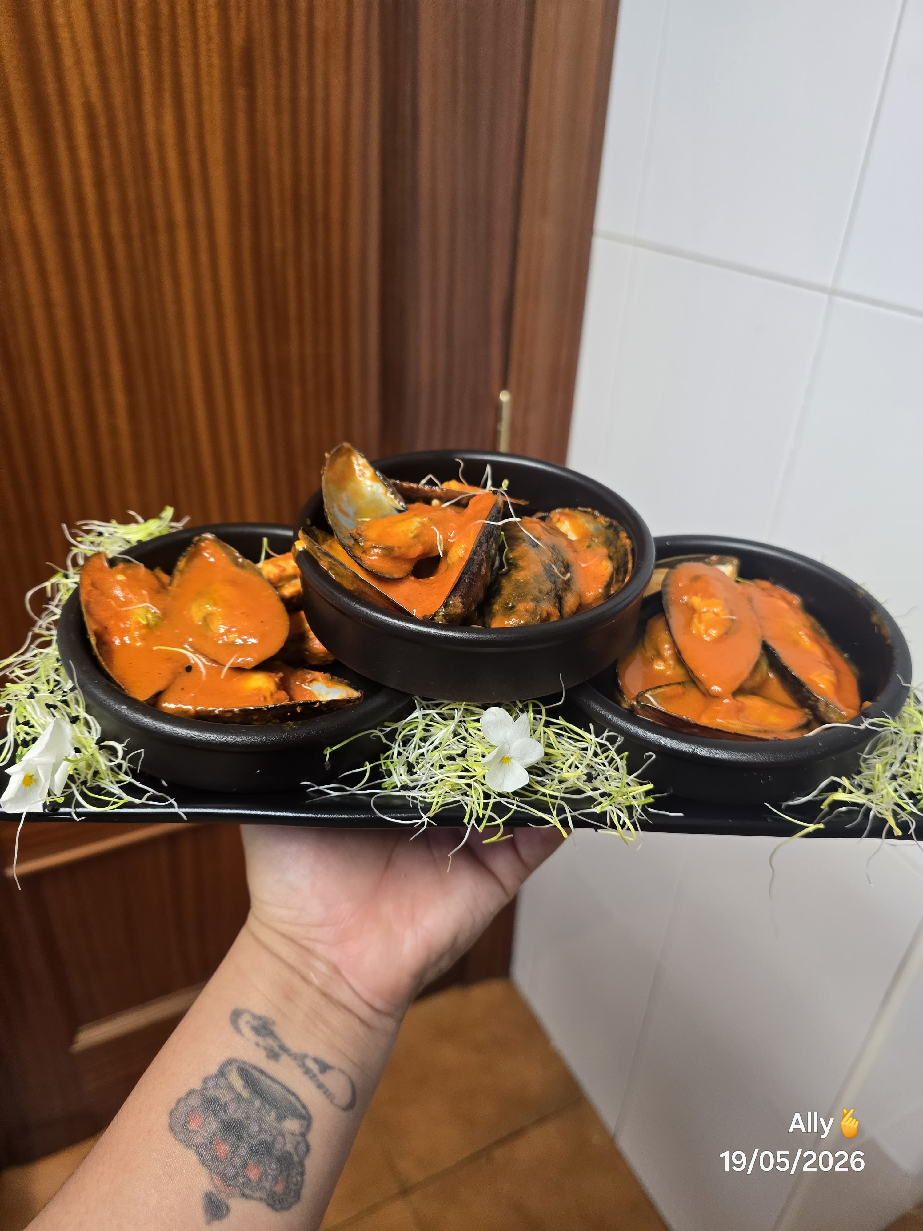 Mejillones en salsa naranja sobre brotes frescos.