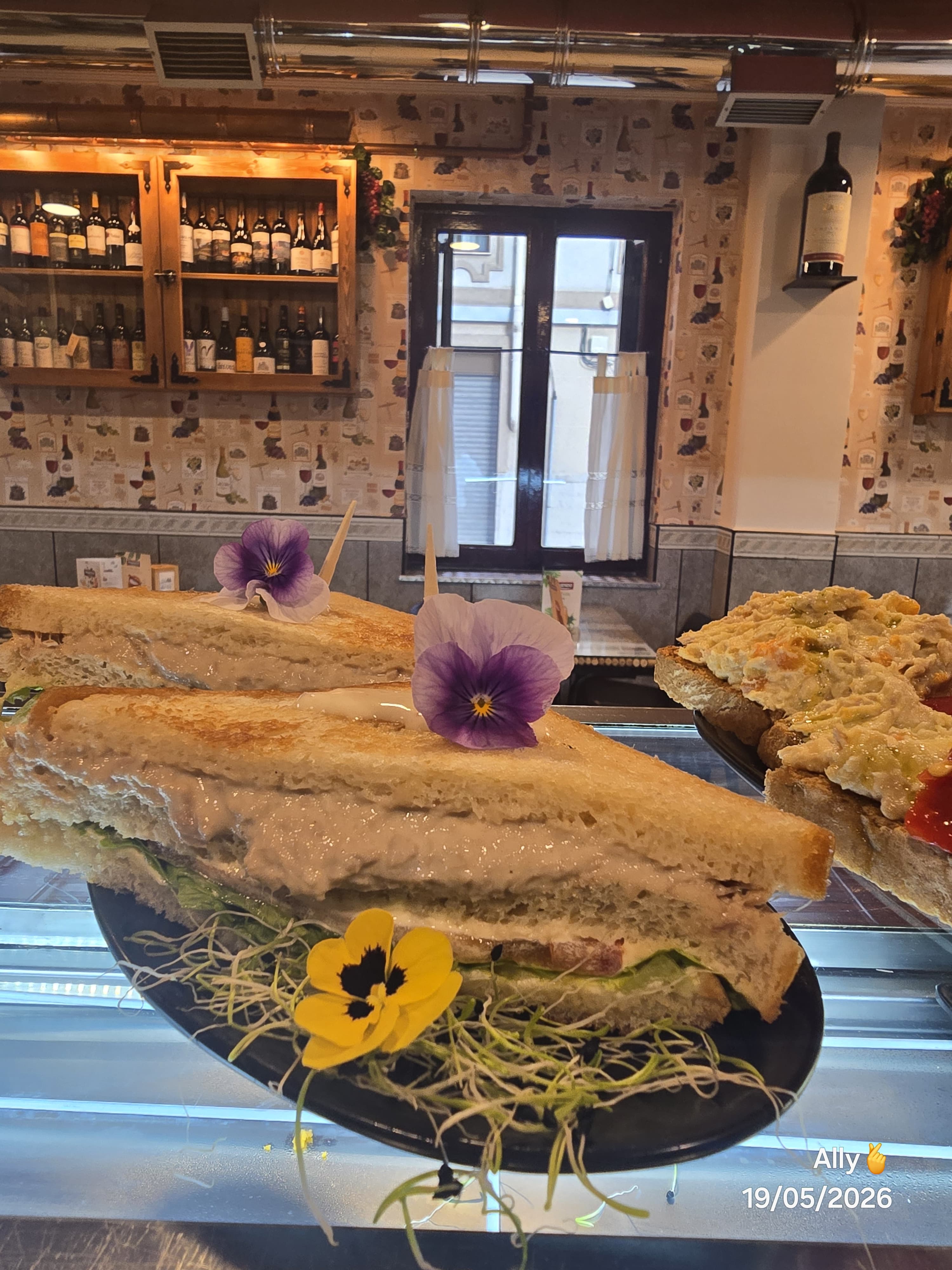 Sándwiches generosos con flores comestibles sobre la barra.